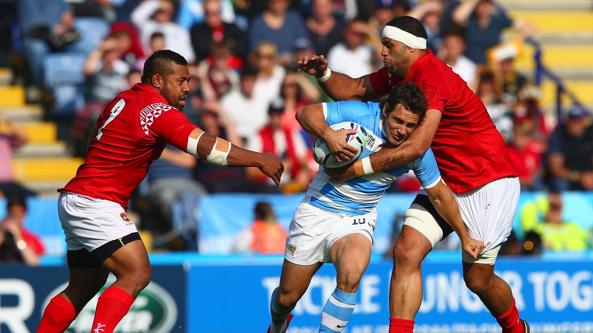 Die Spieler scheinen es zu bemerken.  Nicolas Sanchez tankt sich gegen zwei Spieler Tongas durch