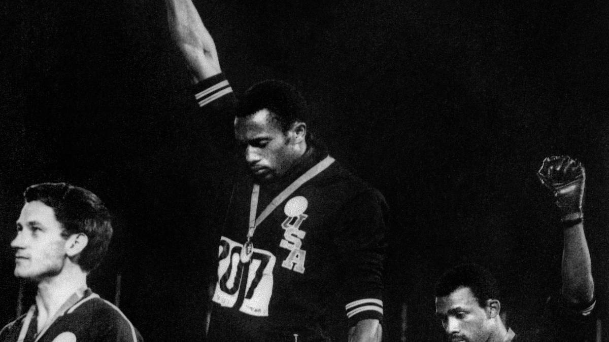 Als Botschafter ihres Volkes fühlten sich 1968 auch die dunkelhäutigen US-Läufer Tommie Smith (M.) und John Carlos (r.). Bei der Siegerehrung für Gold und Bronze im 200-m-Lauf traten sie zunächst in Socken aufs Podest, während der Nationalhymne streckten sie eine mit schwarzen Handschuhen bedeckte Faust in den Himmel - ein stiller Protest für die Rechte der Afro-Amerikaner