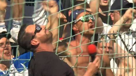 Arminia Bielefeld feiert in Unterhaching seinen Aufstieg in die 2. Bundesliga. Trainer Mitch Kniat heizt die Fans auf dem Zaun ein.