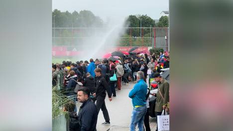 Die erste öffentliche Trainingseinheit des FC Bayern ist von schlechtem Wetter geprägt. Dennoch bildet sich an der Säbener Straße eine große Schlange.