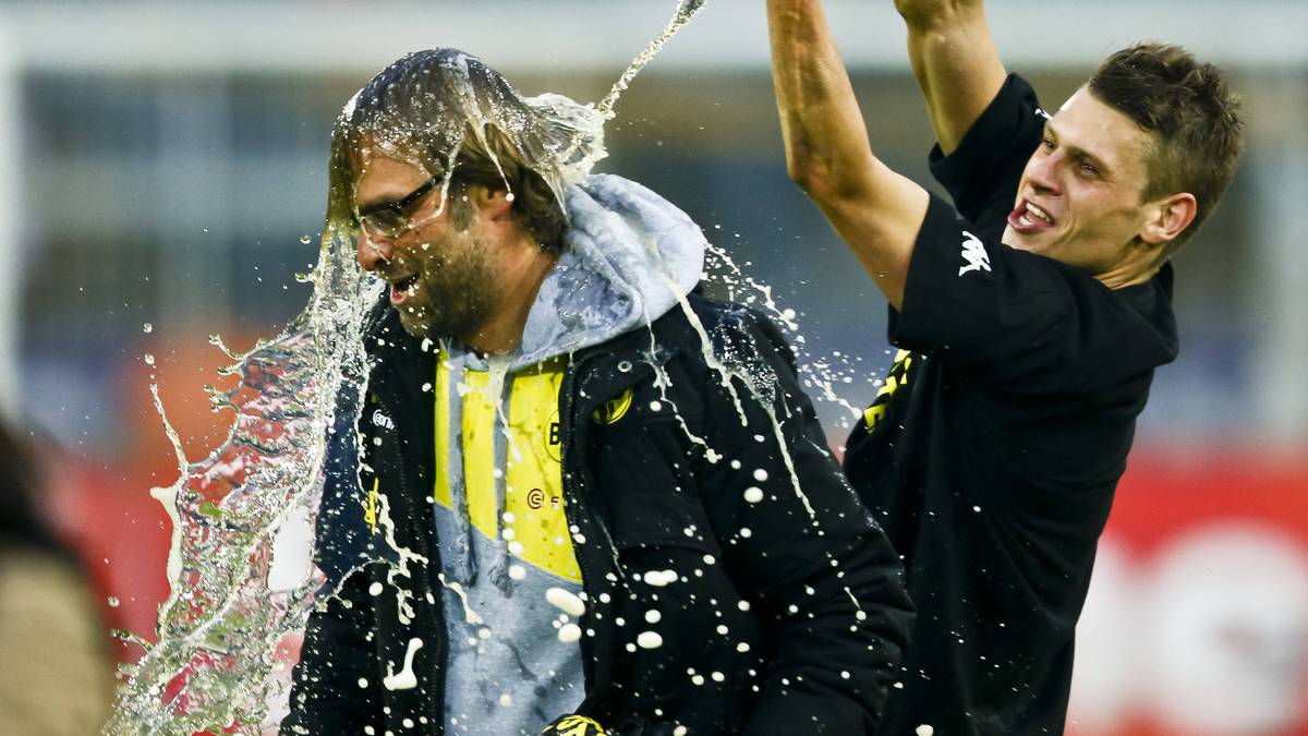 Dortmund ist der erste Meister der Geschichte, der die 80-Punkte-Marke knackt. Da muss Klopp auch die Bierdusche von Lukasz Piszszek über sich ergehen lassen