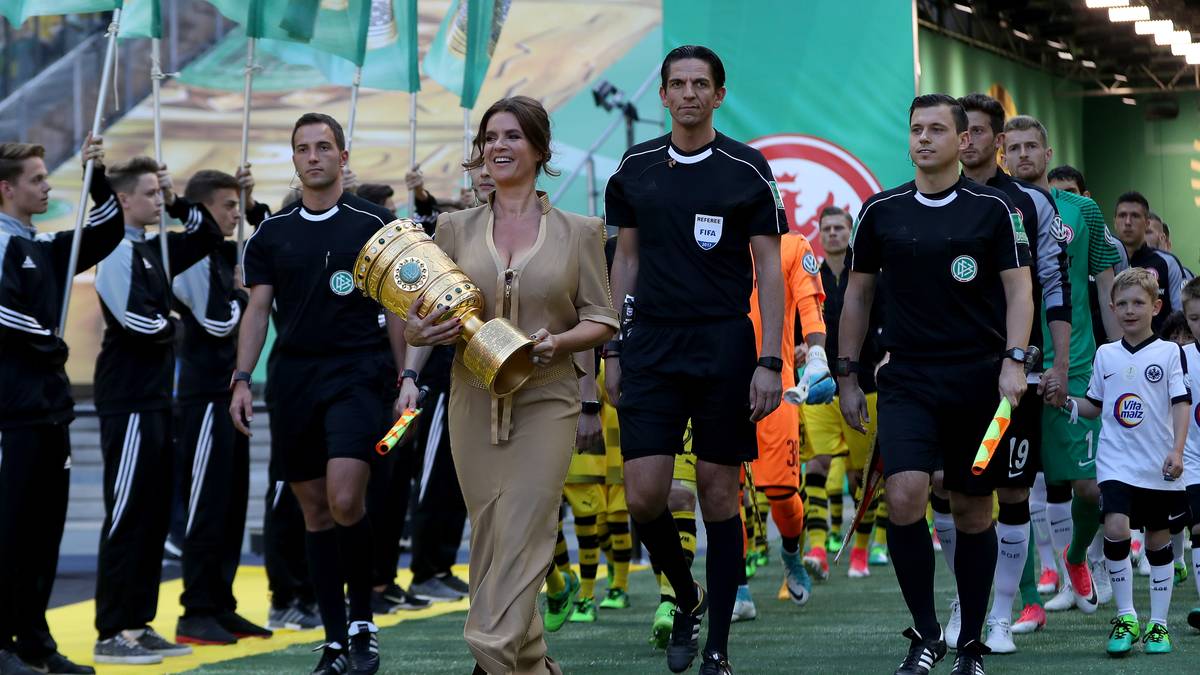 Dann kommt der Pott, ins Stadion getragen von Eiskunstlauf-Queen Katarina Witt. Schiedsrichter ist der Franke Deniz Aytekin (M.)