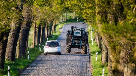 Landwirtschaftliche Fahrzeuge können Erntereste und rutschigen Dreck auf der Fahrbahn hinterlassen.