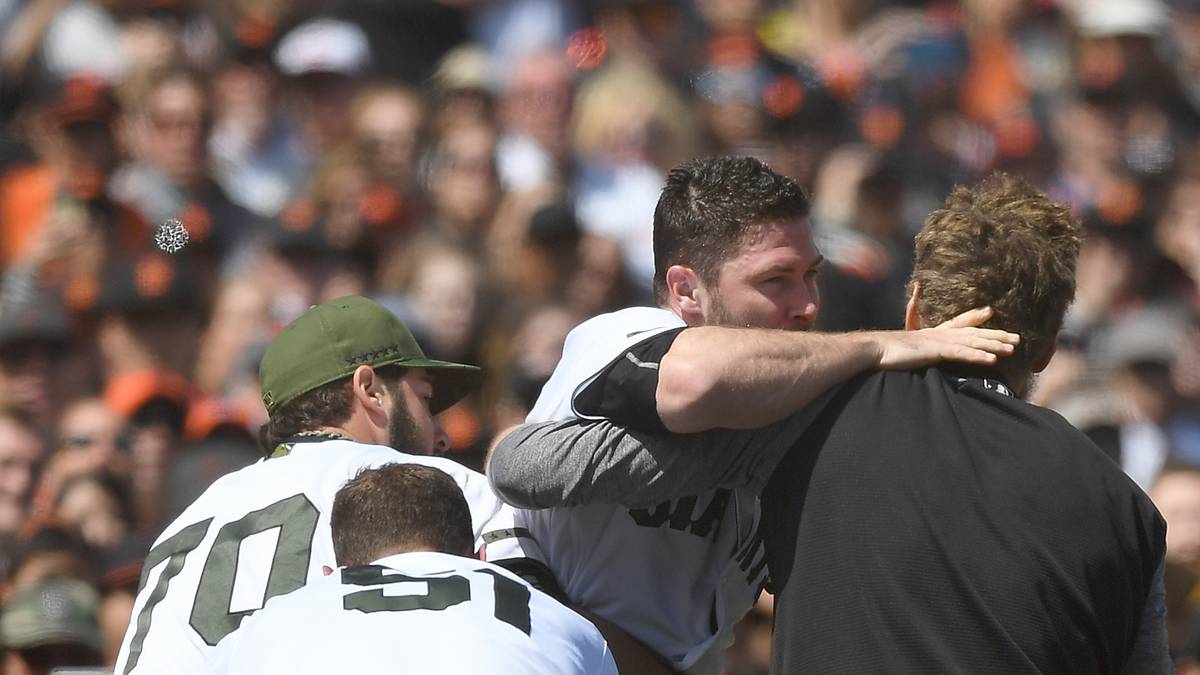 Strickland wird schließlich unter großer Mühe von drei Personen vom Feld geführt 