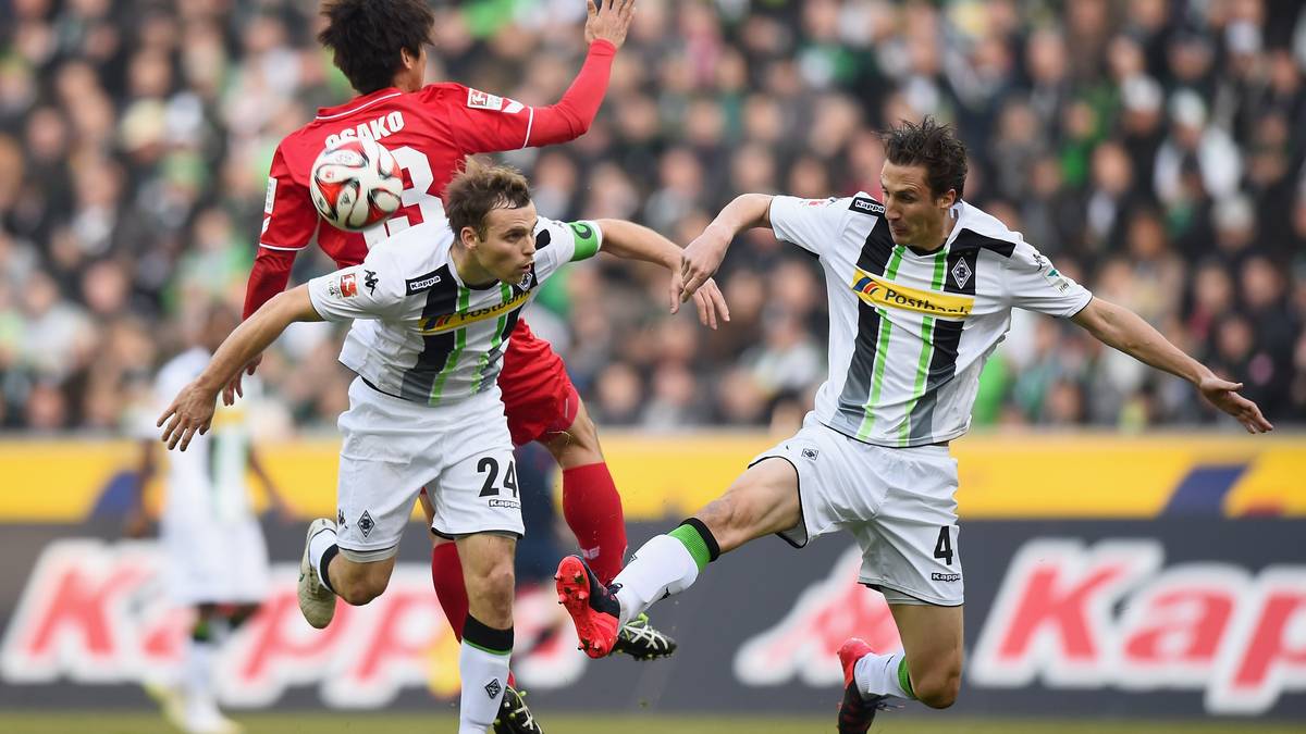 MOENCHENGLADBACH, GERMANY - FEBRUARY 14: Yuya Osako of 1.FC Koeln is challenged by Tony Jantschke of Borussia Moenchengladbach and Roel Brouwers of Borussia Moenchengladbach during the Bundesliga match between Borussia Moenchengladbach and 1. FC Koeln at Borussia Park Stadium on February 14, 2015 in Moenchengladbach, Germany.  (Photo by Lars Baron/Bongarts/Getty Images)