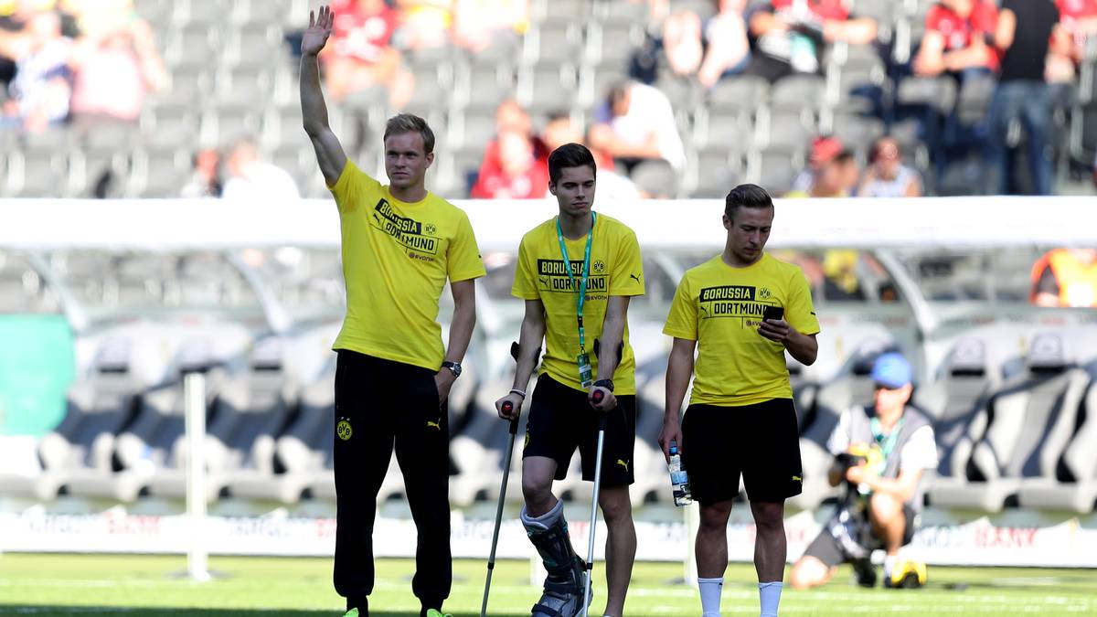 Der am Sprunggelenk schwer verletzte Julian Weigl ist auch im Stadion und humpelt dick bandagiert über den Platz