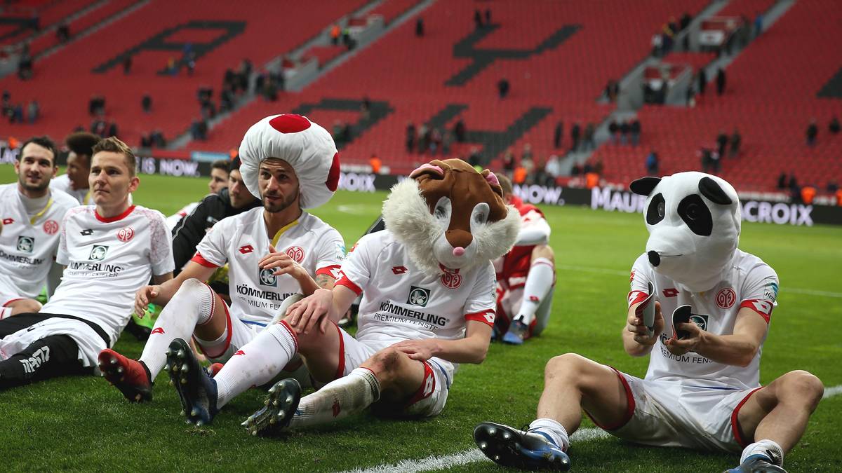 Die Mainzer Spieler decken sich mit lustigen Kopfbedeckungen ein und genießen den Sieg