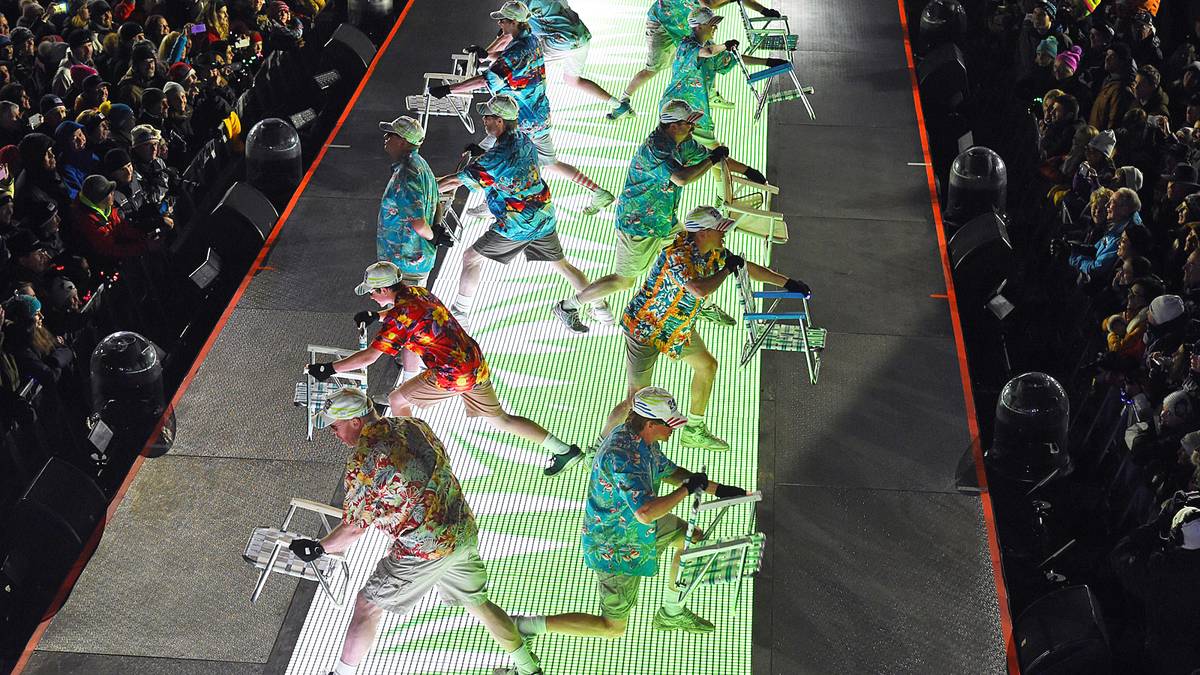 Dieser Auftritt hinterlässt manches Fragezeichen, erinnern diese Bühnenkünstler mit ihren Hawaiihemden und Klappstühlen doch eher an pauschale Sommerurlauber als an Wintersportfans