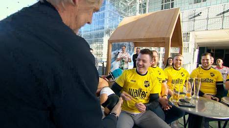 Jan Åge Fjörtoft sorgt mal wieder für beste Unterhaltung. Während im Doppelpass gerade ein Fan interviewt wird, stürmt der Norweger plötzlich mit dem Phrasenschwein ins Bild und kassiert lachend ab. 