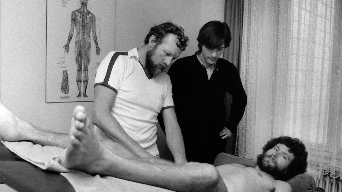 Müller-Wohlfahrt bei der Arbeit: Ein angeschlagener Paul Breitner muss behandelt werden. Über die Jahre erarbeitet sich der Mediziner einen ausgezeichneten Ruf. Lothar Matthäus spricht von "Radarfingern”, Boris Becker vergleicht seine Arbeit mit einem "seelischen Wannenbad”