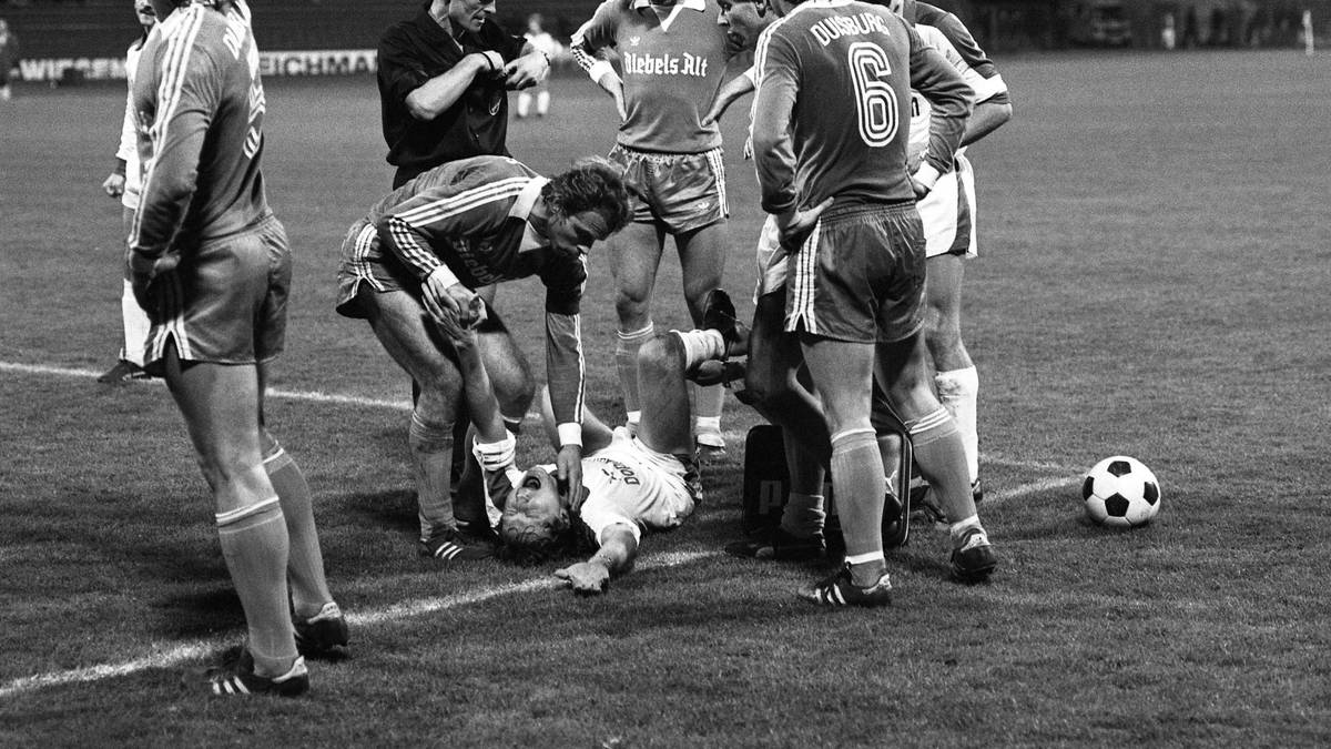Das grobe Einsteigen des damaligen Duisburgers Paul Steiner beendet 1979 die Karriere von Nationalspieler Heinz Flohe (unten). Der langjährige Kölner steht damals in Diensten von 1860 München. Flohe, Weltmeister von 1974, erleidet einen Schien- und Wadenbeinbruch