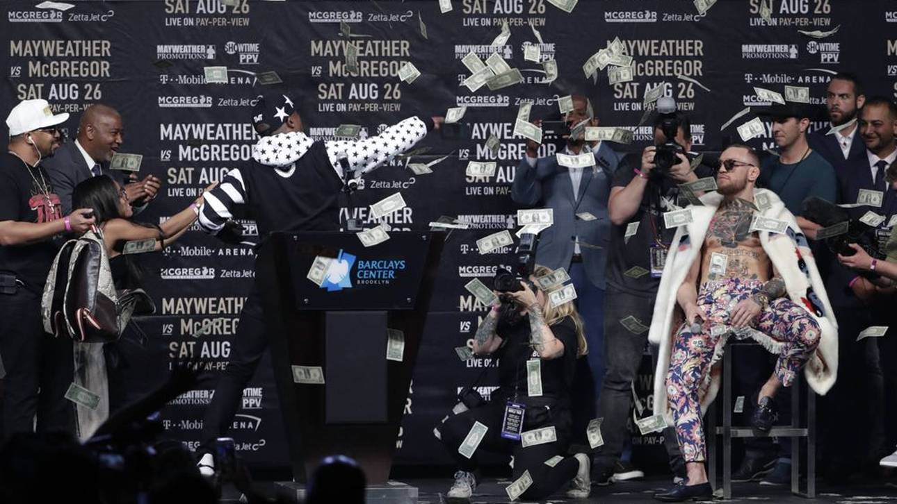 Floyd Mayweather (l.) bewirft Connor McGregor (r.) mit Geld