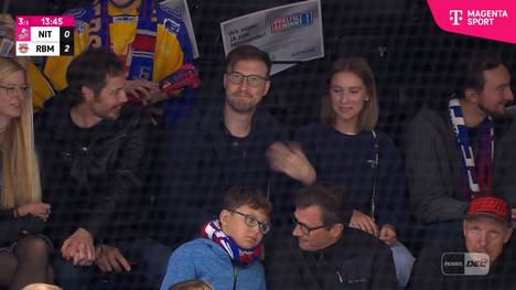 Im Spiel der Münchner Bullen fliegt der Puck über die Bande in den Zuschauerraum. Ein Fan beweist ein glückliches Händchen und fängt die Scheibe, was aber offensichtlich wehtut.