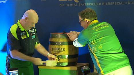 Michael van Gerwen zapft ein Holzfass Erdinger Helles an. Was ein kurioses Bild abgibt, hat einen Hintergrund: Die PDC Europe hat die Traditionsmarke als Getränkepartner gewonnen. 