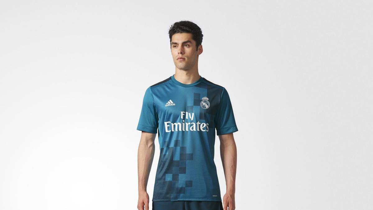 Ein dunkler Farbverlauf, der sich in Quadrate auflöst, prangt quer über der Brust. Die Hose ist ebenfalls dunkel gehalten, die Stutzen sind wieder Türkis. Traum oder Trauma? Wer's mag...