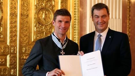 MUNICH, GERMANY - DECEMBER 03: Bavarian Prime Minister Markus Soeder (R) awards Thomas Mueller of FC Bayern Muenchen with the Bavarian Order Of Merit at Prinz-Carl-Palais on December 03, 2019 in Munich, Germany. (Photo by Alexander Hassenstein/Bongarts/Getty Images)