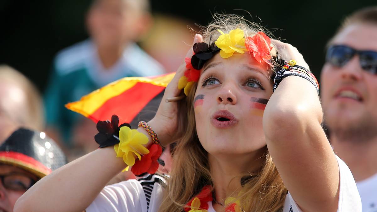 Voll vertieft und fassungslos ist diese Deutsche auf der Fanmeile in Berlin. Sie trägt drei schicke Blumenketten in Deutschlandfarben