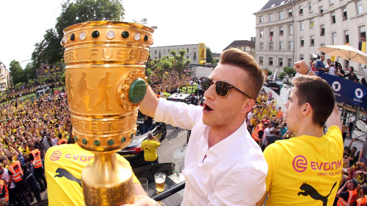 Der wegen seiner Behandlung im Krankenhaus mit Verspätung angekommene Reus ergattert sich sofort den Pokal...