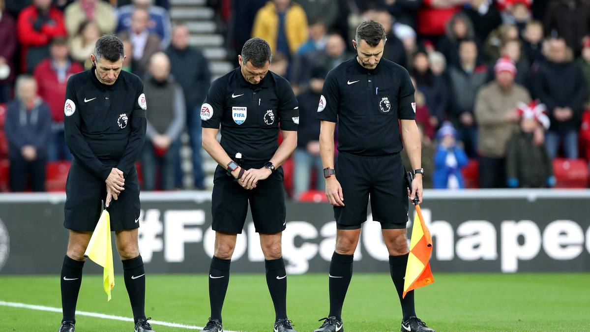 Die Schiedsrichter senken vor dem Anpfiff die Köpfe. Auch den Unparteiischen geht die Tragödie sichtliche nahe