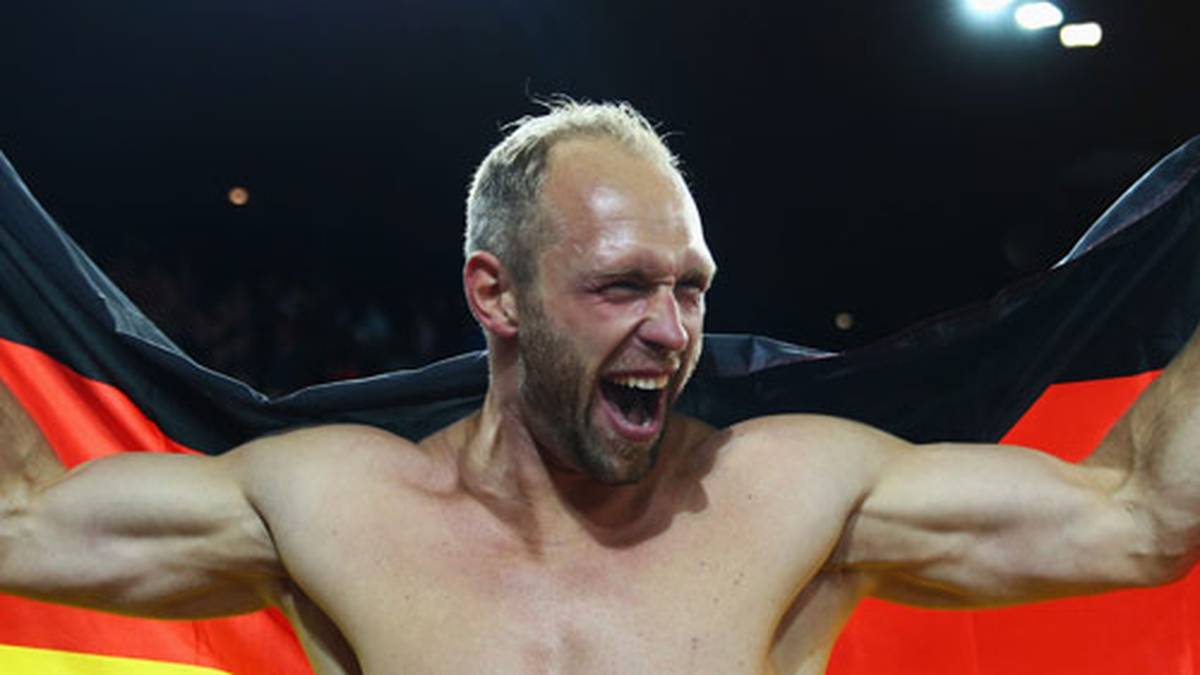 Das kennen wir von ihm. Robert Harting streift die deutsche Fahne über seinen muskulären Körper