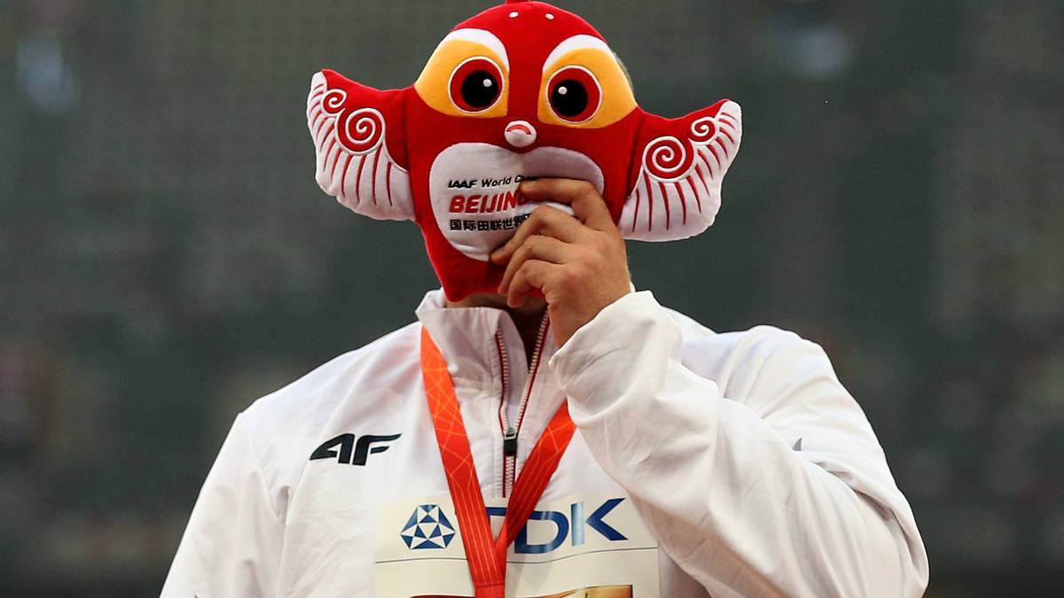 Offenbar wollen die Goldmedaillengewinner alle nicht ihr Gesicht zeigen. Der Pole Piotr Malachowski hält sich bei der Siegerehrung jedenfalls eine Drachenmaske vor das Gesicht