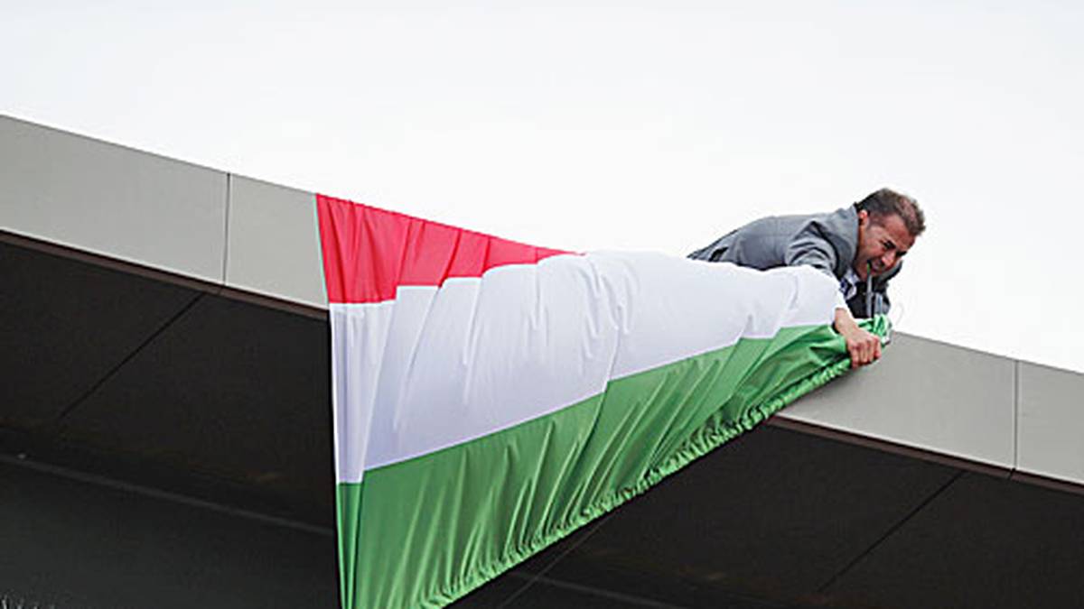 Schwerstarbeit für diesen Helfer. Er versucht eine Flagge vom Stadiondach zu entfernen. Es ist scheinbar schwerer, als man denken mag