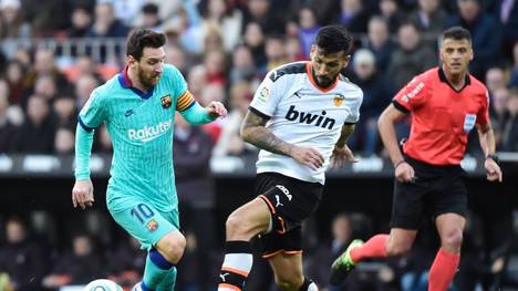 Valencia's Argentinian defender Ezequiel Garay (C) challenges Barcelona's Argentine forward Lionel Messi(L) during the Spanish league football match Valencia CF against FC Barcelona at the Mestalla stadium in Valencia on January 25, 2020. (Photo by JOSE JORDAN / AFP) (Photo by JOSE JORDAN/AFP via Getty Images)