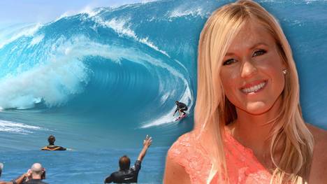 Bethany Hamilton strahlt in die Kamera, im Hintergrund eine Welle mit Surfern