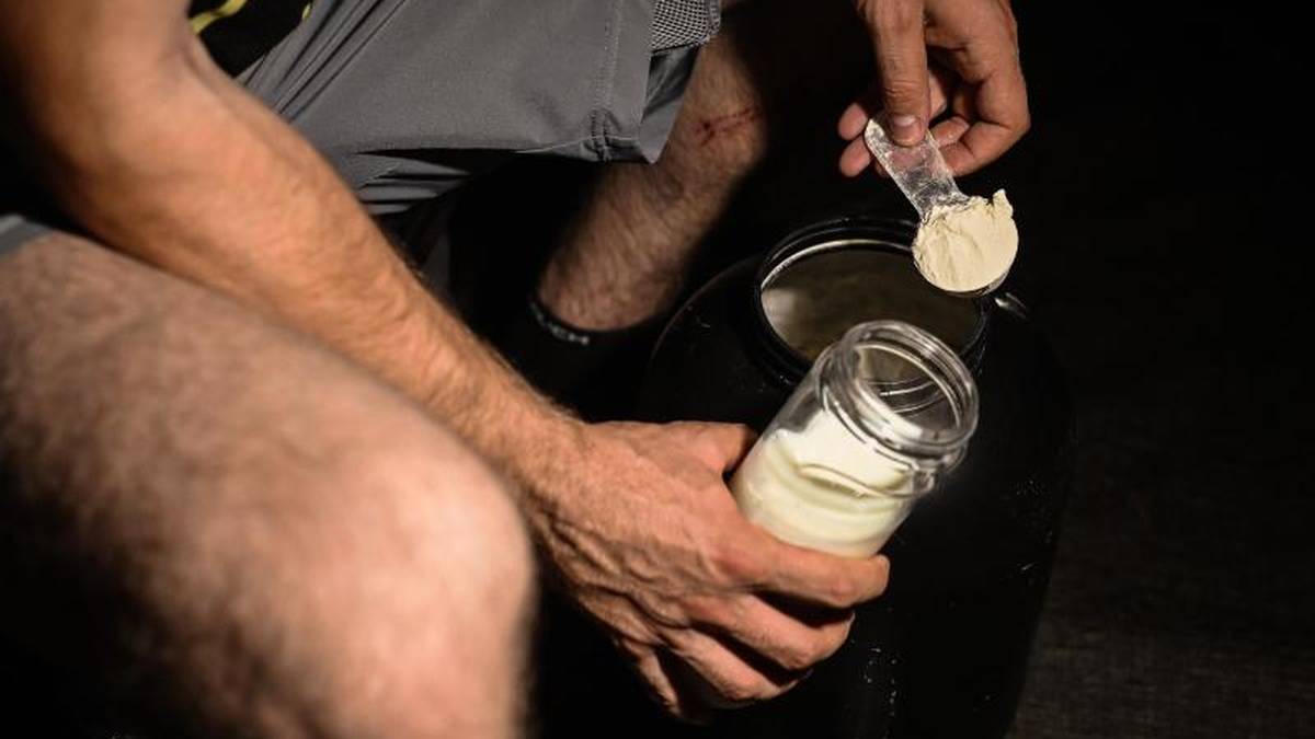 Ein Mann mischt sich nach dem Training Proteinpulver in seinen Shaker
