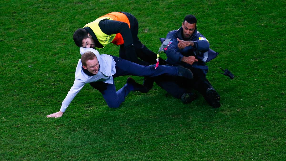 Ein Flitzer muss ebenfalls einiges einstecken. Mit einem sauberen Tackling stoppen zwei Ordner den Platzsturm eines Anhängers