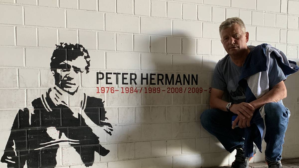 Stolz posiert Hermann vor einem Graffitti innerhalb des Stadions, das an die erfolgreiche Zeit von ihm in Leverkusen erinnert. Hermann war Co-Trainer in Leverkusen, Nürnberg, Hamburg, Schalke, Düsseldorf und München