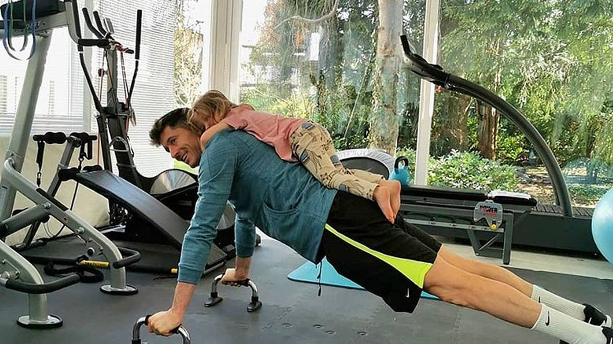 Bayerns Stürmerstar Robert Lewandowski hält sich im heimischen Fitnessraum fit und - nutzt Tochter Klara gleich einmal als zusätzliches Gewicht