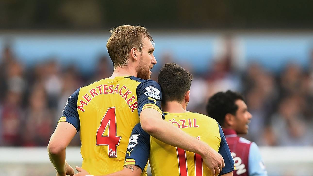 Per Mertesacker und Mesut Özil vom FC Arsenal laufen Arm in Arm