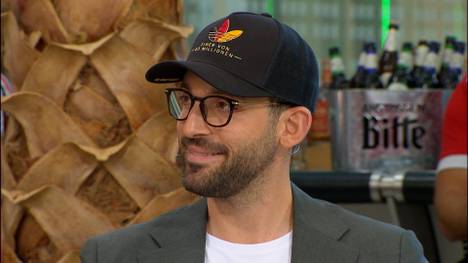 Auf der DFB-Pressekonferenz setzte Bundestrainer Jürgen Klopp ein Statement mit seiner Kappe: "Einer von 83 Millionen!" Patrick Berger hat sich ein Utensil davon geschnappt und sitzt damit plötzlich im Firockx Doppelpass.