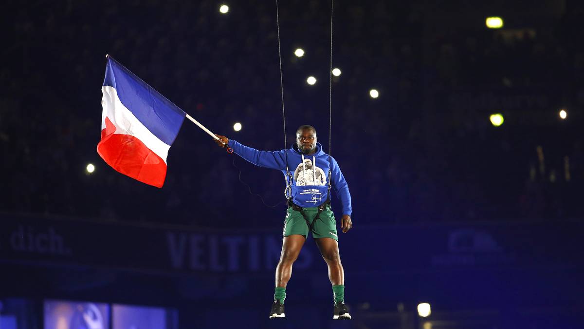 Große Gesten, große Emotionen: Das Abschiedsspiel von Gerald Asamoah auf Schalke steht noch ganz unter dem Eindruck der furchtbaren Terroranschläge von Paris. Asamoah zeigt seine Solidarität mit den Opfern und schwenkt die französische Fahne, während er an Stahlseilen durch die Arena schwebt