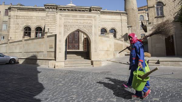 Eine Frau läuft nach den Europaspielen mit Besen und Eimer durch Baku