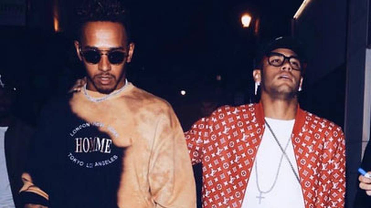 Auch am Tag zuvor sind die beiden in der englischen Hauptstadt unterwegs. Hat Hamilton etwa eine zerschnittene Lederjacke an? Nein, die braune Farbe ist tatsächlich Teil seines T-Shirts