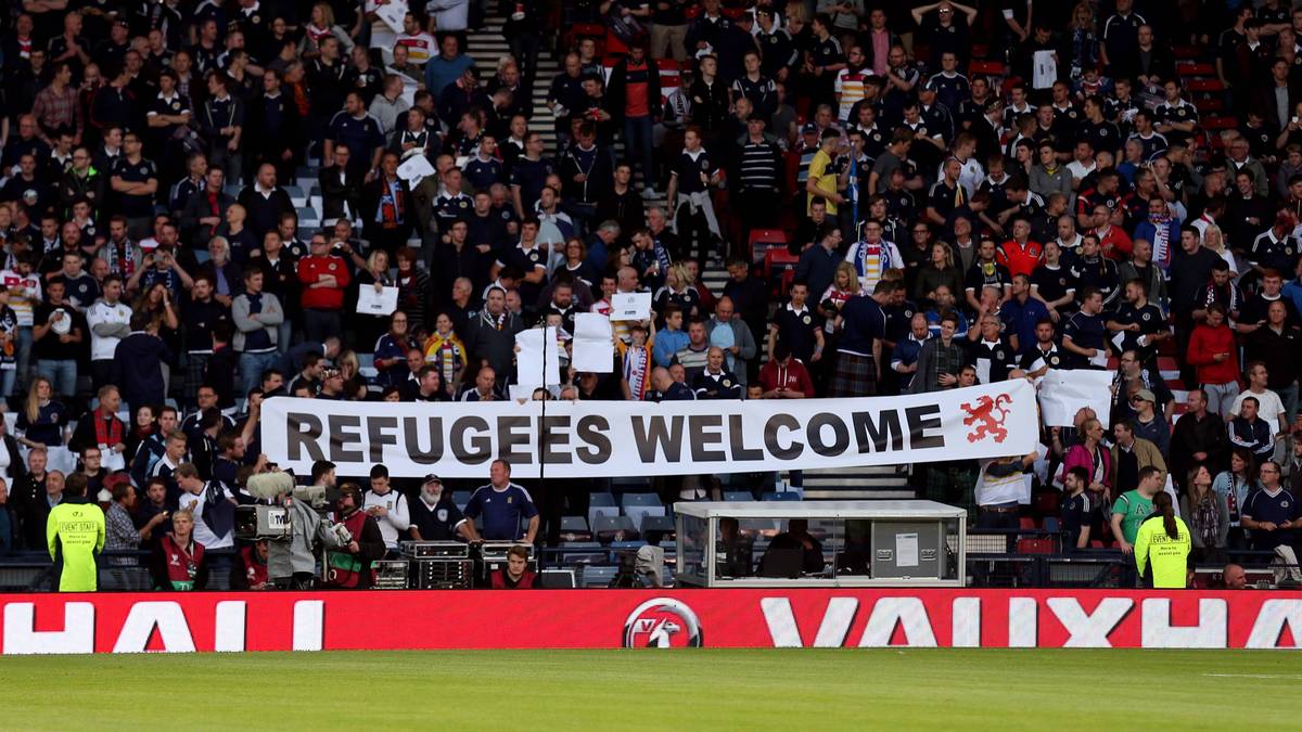 Natürlich ist die Flüchtlingskrise in Europa auch auf der Insel ein Thema. Schottlands Fans setzen vor dem Anpfiff ein Zeichen und zeigen sich solidarisch mit den Flüchtlingen