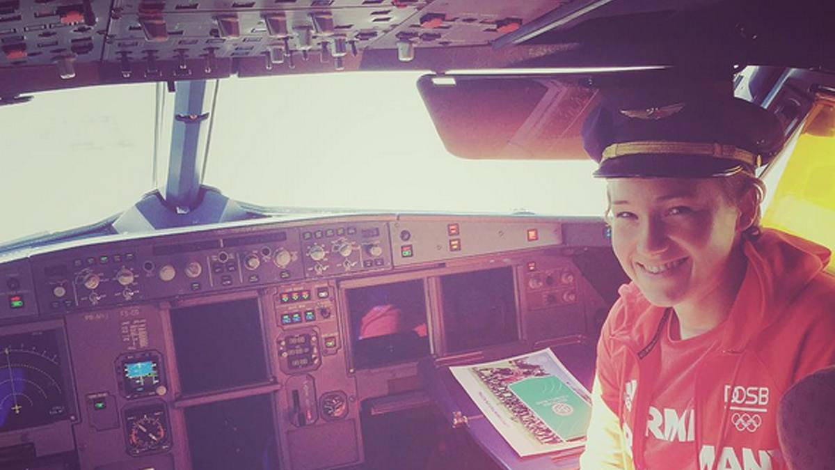 Fußballerin Josphine Henning sitzt mit Piloten-Mütze auf dem Kopf im Cockpit des Fliegers, der das DFB-Team zum Viertelfinale nach Salvador bringt