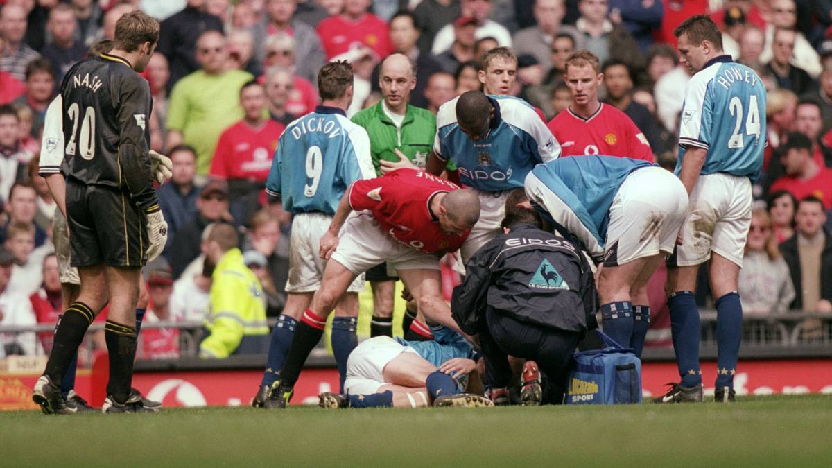 Im Manchester-Derby geht im Jahr 2001 eine Karriere zu Ende. Citys Alf Inge Haaland (unten) wird von Roy Keane (M.) so schwer am Bein verletzt, dass er seine Laufbahn in Folge der Läsionen beenden muss. Die Tat gilt als Revanche-Foul, vier Jahre zuvor hat sich der Ire in einem Zweikampf mit Haaland schwer verletzt