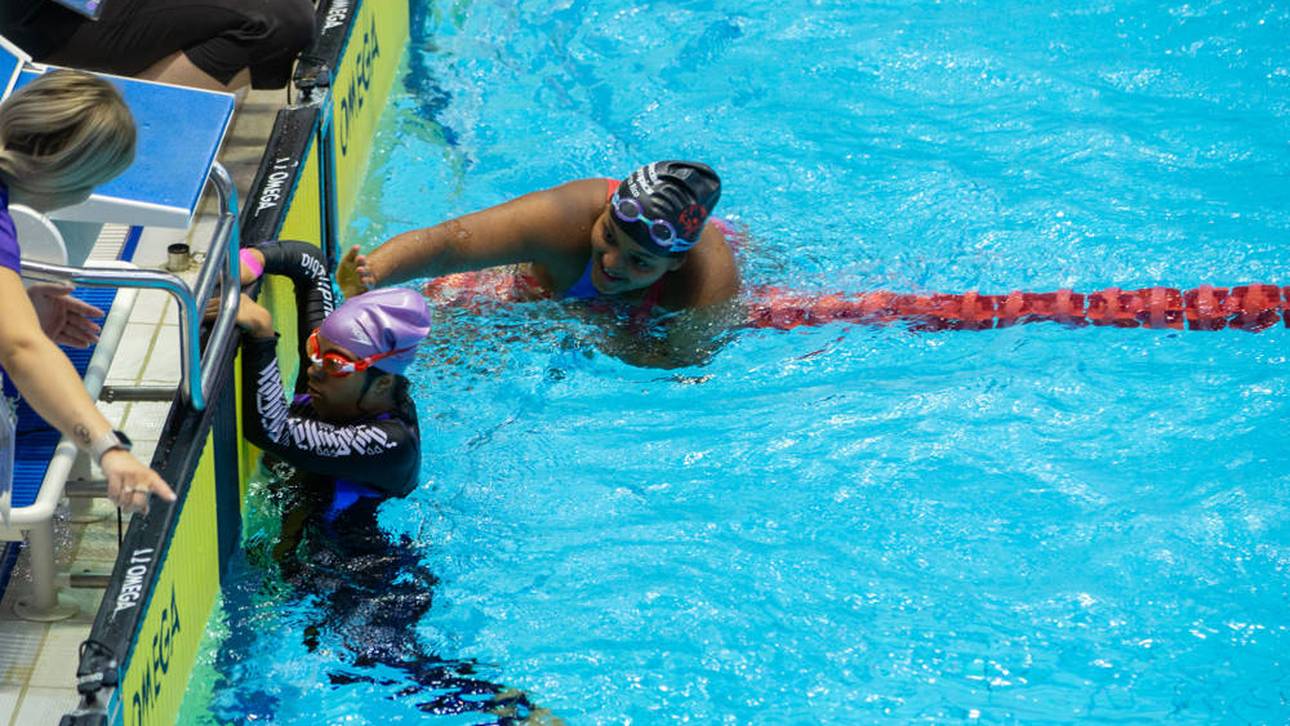 Bewegende Geste: Athletin schwimmt mit anderer Athletin