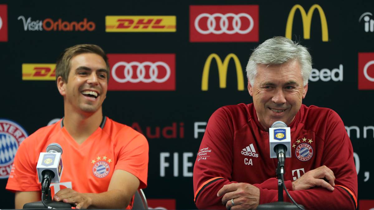 Dann geht der Ernst des Lebens los, doch selbst da herrscht gute Laune. Philipp Lahm (l.) und Trainer Carlo Ancelotti stehen auf einer Pressekonferenz Rede und Antwort