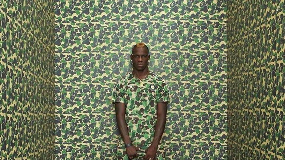 Ton in Ton, Muster in Muster. Mario Balotelli macht eindrucksvoll vor, wie man vor einer Wand im Camouflage-Look nicht auffällt: Einfach passend zur Wand anziehen! Und wenn es dann noch die Tasche im passenden Muster gibt, ist die Style-Krone sicher