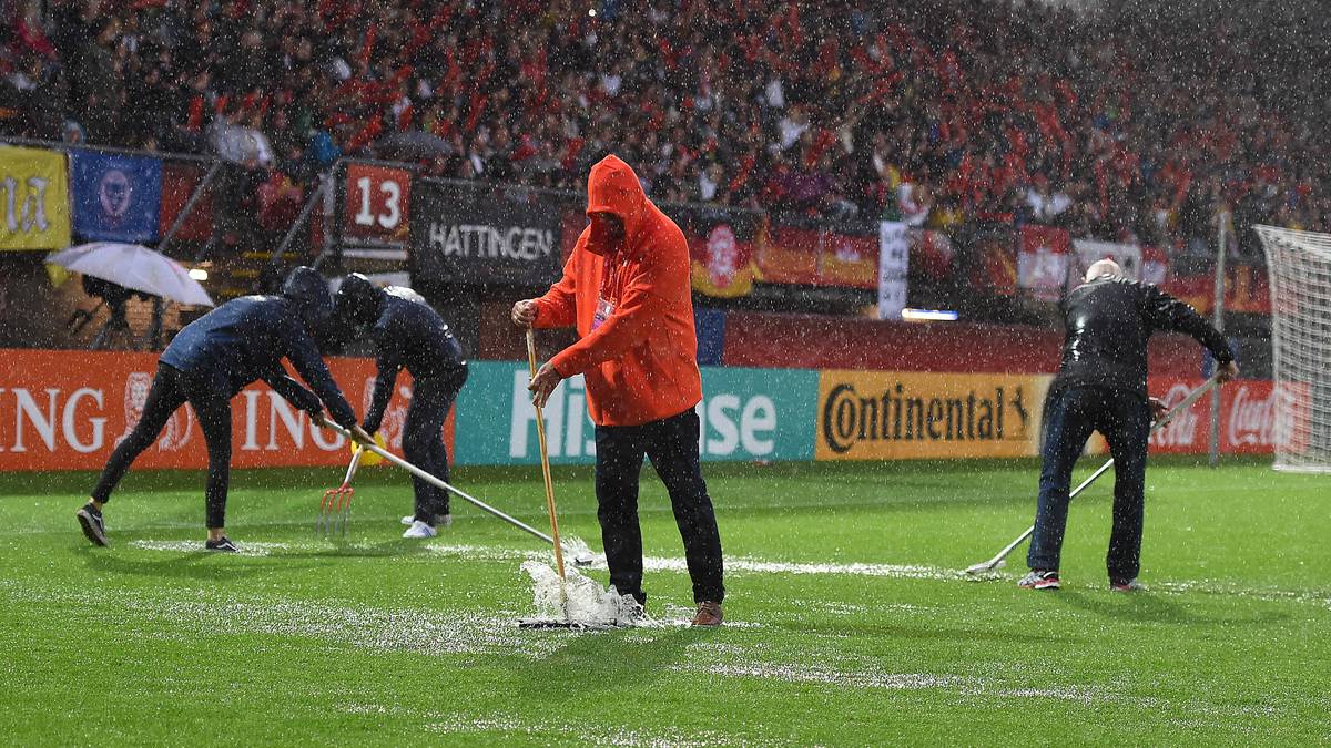 Helfer versuchen unter Hochdruck, die Wassermassen mit Abziehern vom Feld zu schieben