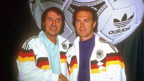Udo Jürgens posiert zusammen mit Franz Beckenbauer in den legendären WM-90-Traingsjacken der deutschen Herren-Fußballnationalmannschaft