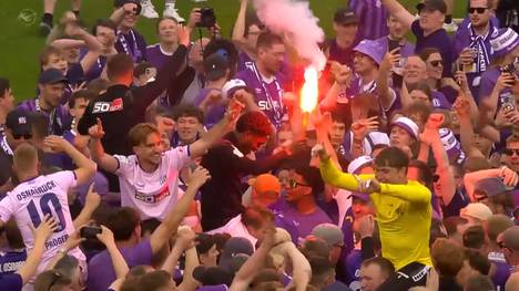 Der VfL Osnabrück ist nach dem Sieg gegen SV Wehen Wiesbaden Meister der 3. Liga und feiert den Aufstieg. Nach Abpfiff stürmen Fans den Platz und feiern ausgelassen mit der Mannschaft.