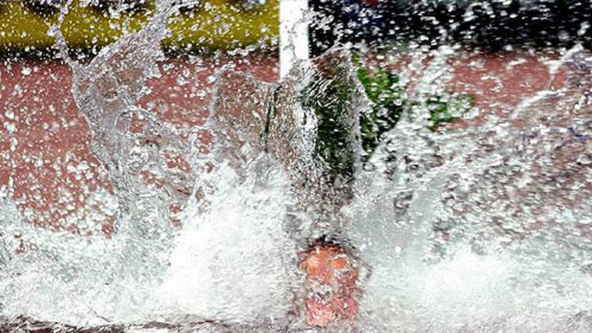 Hier taucht ein Läufer bei den 3000-Meter-Hindernis im Wassergraben ab