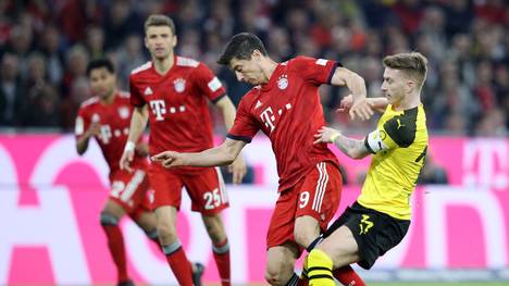 MUNICH, GERMANY - APRIL 06: Robert Lewandowski of Bayern Munich is challenged by Marco Reus of Borussia Dortmund during the Bundesliga match between FC Bayern Muenchen and Borussia Dortmund at Allianz Arena on April 06, 2019 in Munich, Germany. (Photo by Adam Pretty/Bongarts/Getty Images)