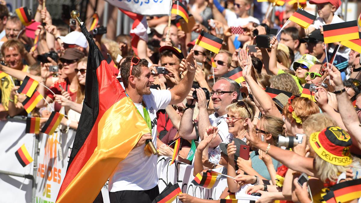 Durchs dichte Spalier trägt Doppel-Olympiasieger Sebastian Brendel wie bei der Schlussfeier die deutsche Fahne
