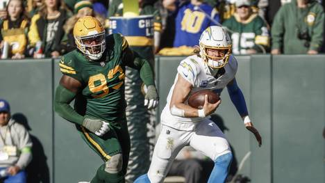 Los Angeles Chargers quarterback Justin Herbert (R) scrambles away from Green Bay Packers defensive tackle T.J. Slaton (L) during the NFL, American Football Herren, USA game between the Los Angeles Chargers and the Green Bay Packers at Lambeau Field on Sunday, November 19, 2023. PUBLICATIONxINxGERxSUIxAUTxHUNxONLY GBW20231119816 TANNENxMAURY